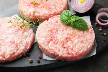 Fresh raw patties for burger and spices on grey table, closeup