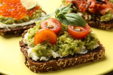 Different delicious avocado sandwiches on plate, closeup