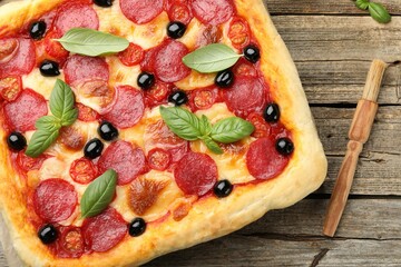 Tasty homemade pizza and brush on wooden table, top view