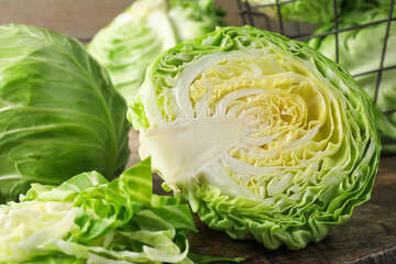 Obraz premium Fresh cut and whole cabbages on wooden table, closeup