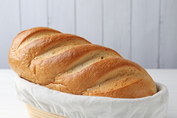 One bread loaf in basket on white table, closeup