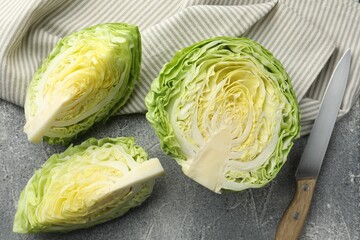 Pieces of fresh cabbage and knife on grey table, flat lay