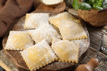 Uncooked ravioli and basil on wooden table, closeup