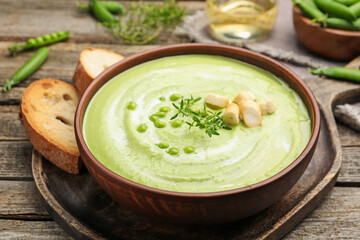 Tasty pea cream soup with croutons and thyme served on wooden table, closeup