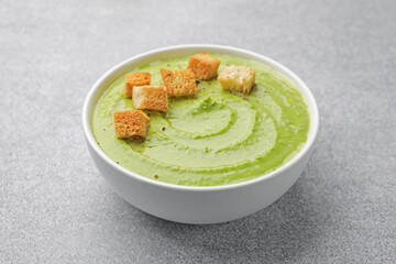 Tasty pea cream soup with croutons on grey table, closeup