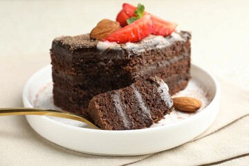 Piece of delicious chocolate cake with strawberry and almonds on table, closeup