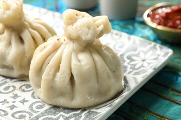 Delicious khinkali served with sauce on table, closeup