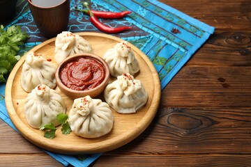 Delicious khinkali served with sauce on wooden table. Space for text