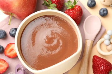 Baby food. Tasty puree in bowl, ingredients and spoon on beige background, flat lay