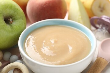 Baby food. Tasty puree in bowl, different ingredients, teether and pacifier on table, closeup
