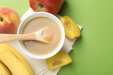 Baby food. Tasty puree in bowl and ingredients on green background, flat lay. Space for text