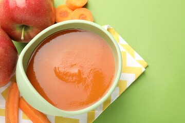 Baby food. Tasty puree in bowl and ingredients on green background, above view. Space for text
