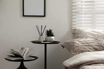 Comfortable bed with beautiful linens, nesting tables and decor in bedroom
