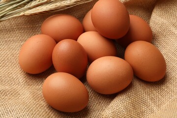 Raw eggs and spikes of wheat on fabric, closeup