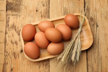 Fresh eggs and spikes on wooden table, top view