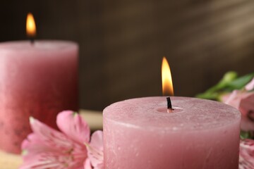 Burning candles and lily flowers on table, closeup