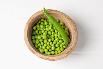 Fresh ripe green peas on white wooden table, top view