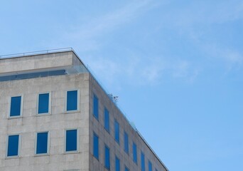 A contemporary building with large windows stands against a bright blue sky