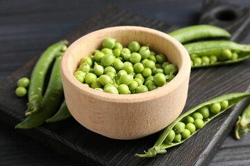 Fresh ripe green peas on black wooden table, closeup