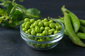 Fresh ripe green peas on black wooden table, closeup