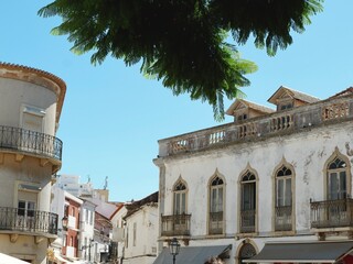 Vibrant town square features beautiful historic buildings under a clear blue sky.
