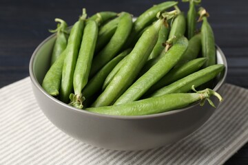 Fresh ripe green peas on black wooden table, closeup