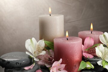 Burning candles and beautiful flowers against light background, closeup