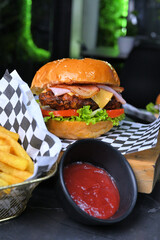 Deliciosa hamburguesa con carne a la parrilla cubierta con verduras, tomates, ketchup, cebollas en...
