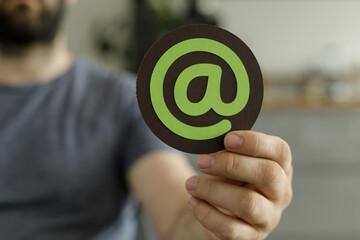 Close-up of a person holding a symbol representing email, ideal for contact us pages and...