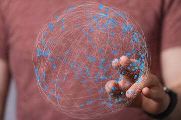 Person's hand interacts with a digital sphere representing a global network connection. Technology,...