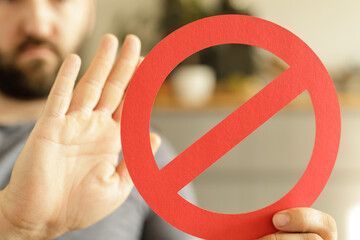 Image of a man holding a stop sign, symbolizing prohibition, denial, or rejection.