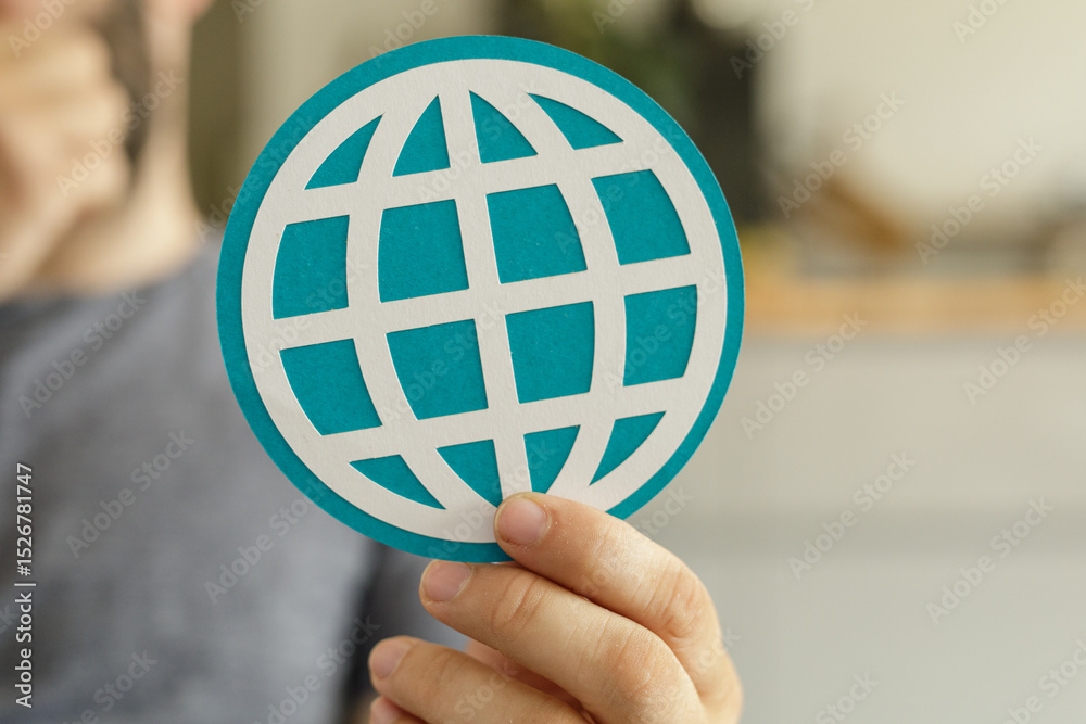 Aufkleber Close-up of a hand holding a teal paper cut-out of a world globe, symbolizing global connection and networking.