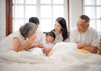 Obraz premium Family gathered indoors enjoying quality time while sharing laughter and stories with a young child in a cozy bedroom