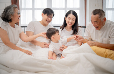 Fototapeta premium Family gathers in cozy bedroom to share joyful moments with toddler during sunny afternoon