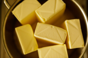 Close-up of golden yellow butter cubes in a bowl. Perfect for recipes or dairy product promotions.
