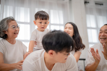 Obraz premium Family sharing joyful moments during a playful gathering with a child on an adult's back in a bright room