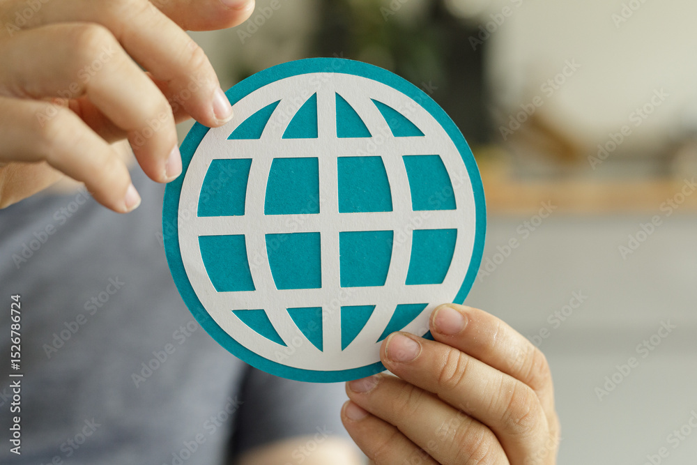 Poster close-up of hands holding a teal paper cut-out of a world globe, symbolizing global connection and i