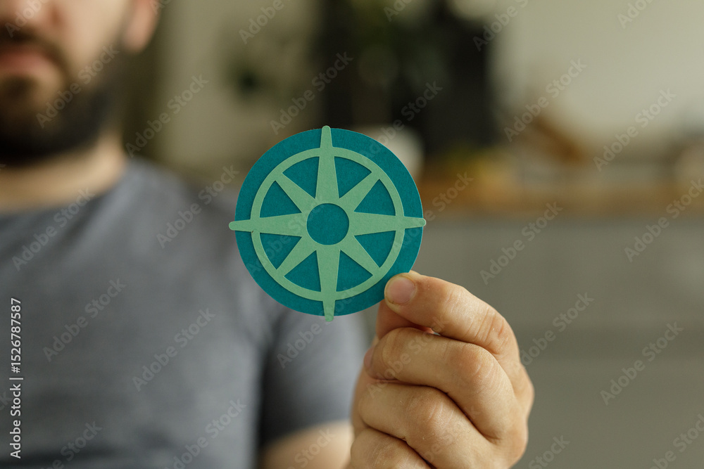 Poster a man holds a paper compass, symbolizing guidance, direction, and finding your way.