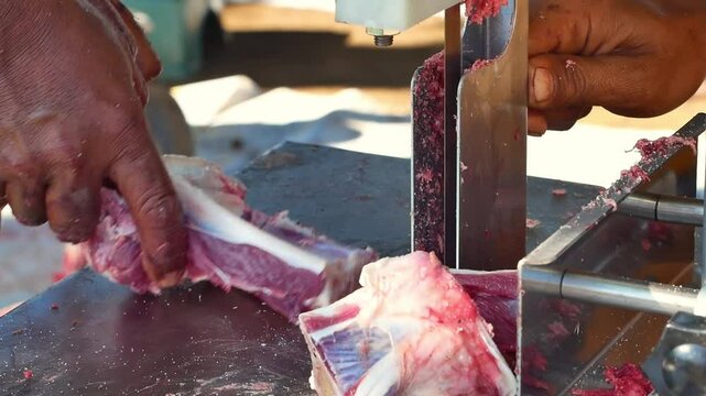The butcher cuts the beef with a special sawing machine. Beef cut using a special meat saw machine. The event of Eid al-Adha cutting meat with a machine.