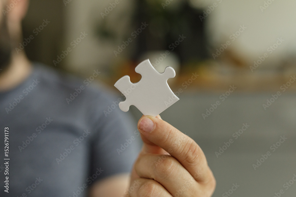 Poster a man holds a single white puzzle piece, symbolizing solutions, teamwork, and problem-solving.
