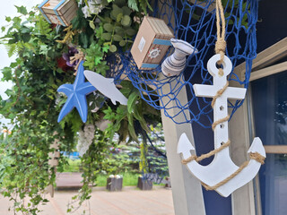 Nautical decor with white anchor and blue starfish amidst green foliage