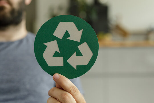 Image of a person holding a recycling symbol, promoting sustainable practices and environmental awareness.