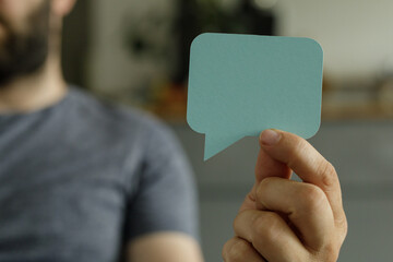 A man holds a blank speech bubble, perfect for communication, feedback, or dialogue concepts.