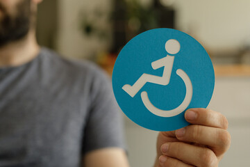 Image of a person holding a blue accessibility symbol. Represents inclusivity and disability...