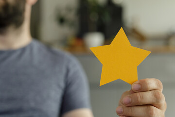 Stock photo of a man holding a golden star, representing customer satisfaction, feedback, and...