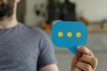 Stock photo of a person holding a speech bubble, symbolizing communication and feedback.