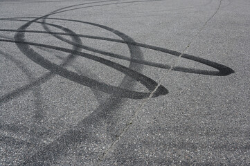 an asphalt surface covered in overlapping tire skid marks from high-speed driving maneuvers such as drifting or burnouts © Mikhail Olykainen