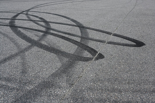 an asphalt surface covered in overlapping tire skid marks from high-speed driving maneuvers such as drifting or burnouts
