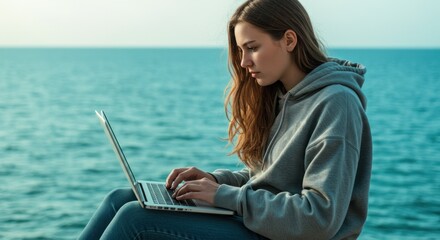 Young person working on laptop by water