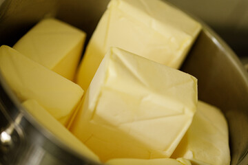 Close-up of several blocks of fresh, creamy butter in a metal bowl. Perfect for baking or cooking.